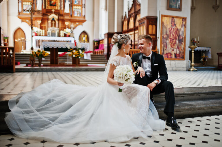 Photosession of stylish wedding couple on catholic church.