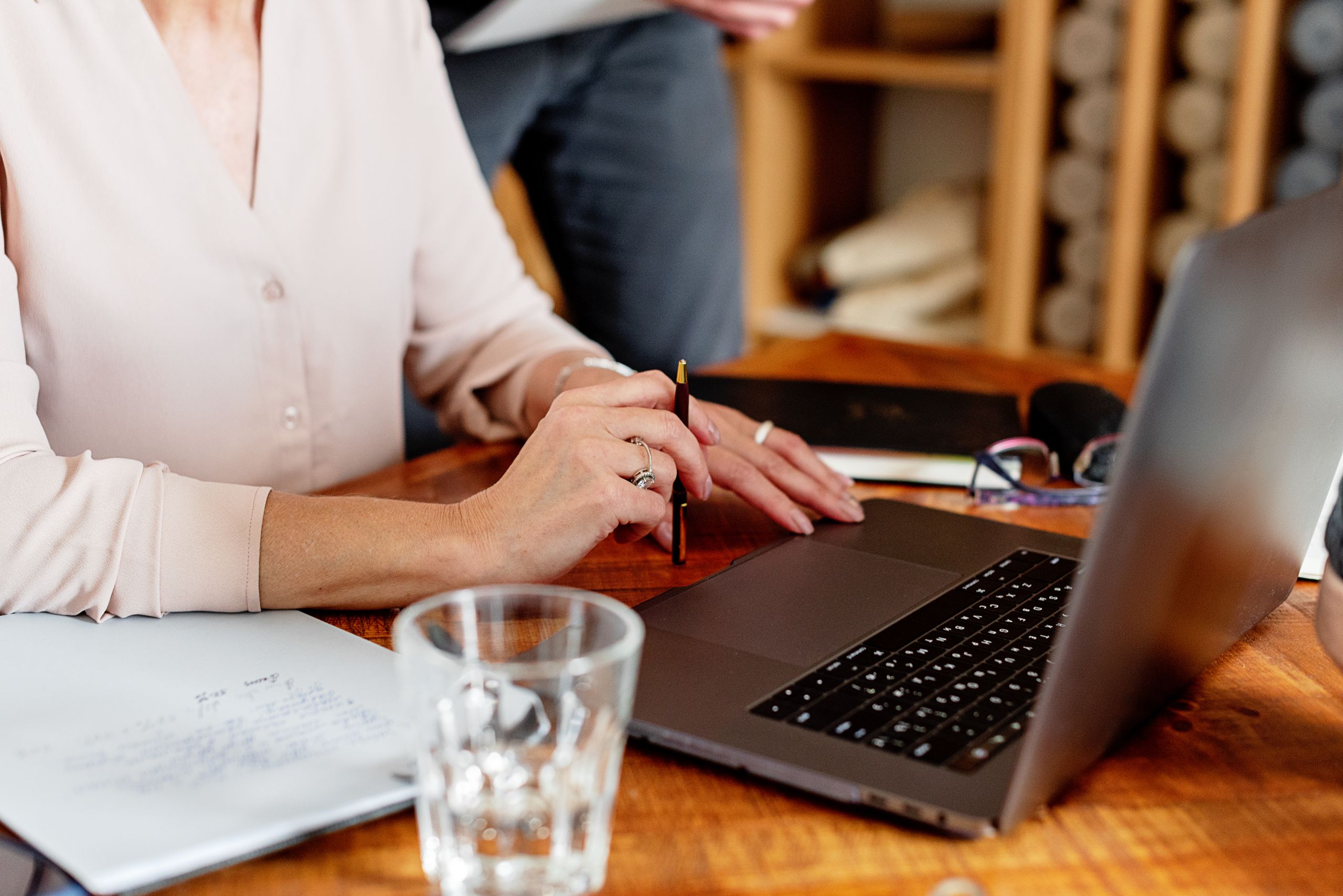 Close-up of a woman working on a laptop with documents on a desk. Ideal for business themes.